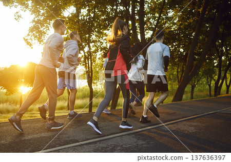 Full-length view, group of people running outdoors on paved path Full-length view, group of people running outdoors on paved path 137636397