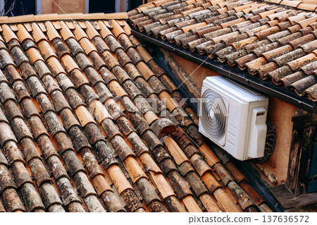 Details of a roof with tiles and an air conditioning unit on a warm day Details of a roof with tiles and an air conditioning unit on a warm day 137636572