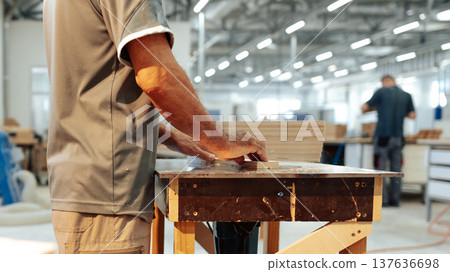 Woodworking activity taking place in a workshop during daytime hours with workers present 137636698