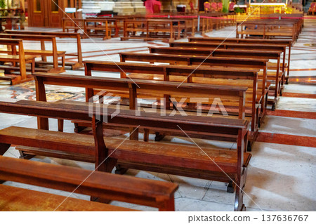 Wooden benches arranged in a church interior during a quiet time of day 137636767