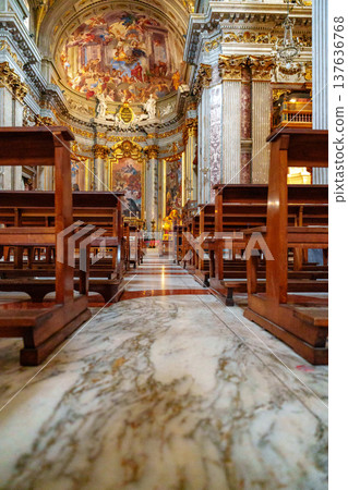 Views of wooden benches and marble floor in a large church with high ceiling and artwork 137636768