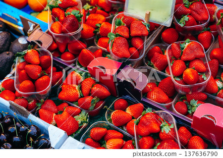 Fresh strawberries displayed in plastic containers at a market on a sunny day 137636790