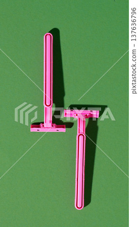 Pink shaving razors placed on a green background during daylight hours Pink shaving razors placed on a green background during daylight hours 137636796