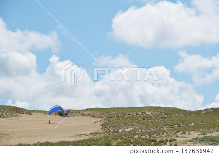 Young people enjoying paragliding in the Tottori sand dunes 137636942