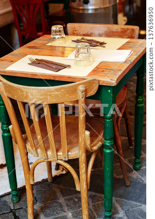 Table and chairs set for dining at a restaurant in a busy area during the day Table and chairs set for dining at a restaurant in a busy area during the day 137636950