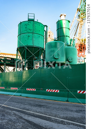 Construction site showing green equipment and machinery near a city street in bright weather Construction site showing green equipment and machinery near a city street in bright weather 137637014