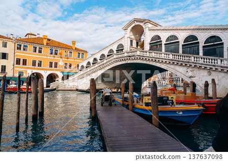 Bridge spans the canal in Venice with boats docked and buildings lining the waterway Bridge spans the canal in Venice with boats docked and buildings lining the waterway 137637098