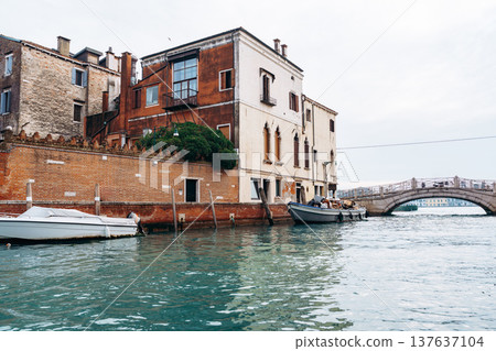 Boats docked near buildings along the canal in Venice during cloudy weather 137637104