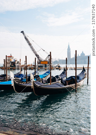 Gondolas docked at the waterfront in Venice near construction and towers Gondolas docked at the waterfront in Venice near construction and towers 137637140