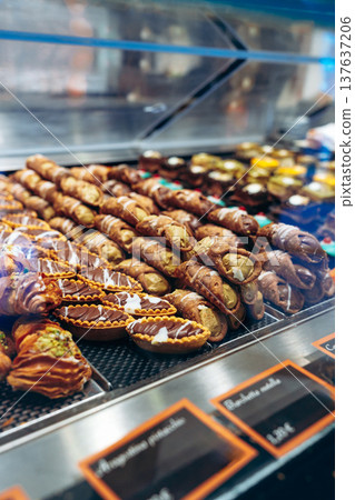 Pastries on display at a bakery showing various types of desserts in a busy shop 137637206