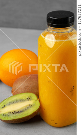 Fresh juice made from fruits displayed on a gray table with a bottle and various fruits Fresh juice made from fruits displayed on a gray table with a bottle and various fruits 137637211