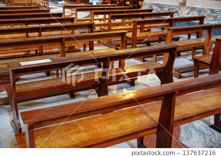 Wooden benches arranged in a church interior during daytime service hours 137637216