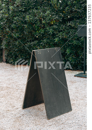 Sign board placed in a garden area near a black object during daytime Sign board placed in a garden area near a black object during daytime 137637235