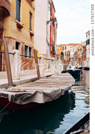 Boats line a quiet canal in Venice during a cloudy day Boats line a quiet canal in Venice during a cloudy day 137637309