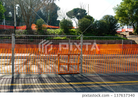 Road closed due to construction work with orange barriers and fenced area near trees Road closed due to construction work with orange barriers and fenced area near trees 137637340