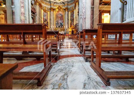 Church interior shows wooden benches placed for worship and reflection during prayer service 137637345