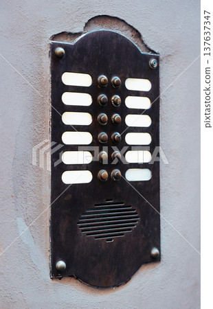 Old metal intercom panel on wall in urban setting with many buttons present Old metal intercom panel on wall in urban setting with many buttons present 137637347