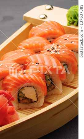 Sushi roll with salmon and ingredients served in a wooden boat tray on a dark table 137637395