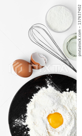 Preparing to bake with flour, eggs, and a whisk on a black plate in a kitchen setting Preparing to bake with flour, eggs, and a whisk on a black plate in a kitchen setting 137637402