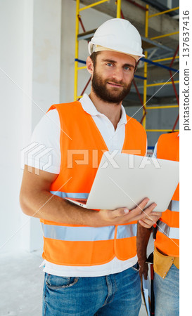 Construction worker using laptop in building site during daytime work hours 137637416