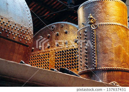 Old metal tanks and machinery in a factory setting with natural light filtering in Old metal tanks and machinery in a factory setting with natural light filtering in 137637431