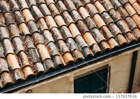 Old roof tiles arranged in a pattern on a building in a city during the daytime Old roof tiles arranged in a pattern on a building in a city during the daytime 137637616