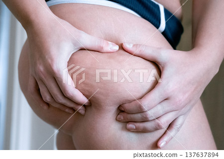 Woman weight awareness. Female checking abdominal area indoors. Woman weight awareness. Female checking abdominal area indoors. 137637894