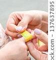 Child healthcare routine. Toddler finger bandaged by mother hands. Daily care concept. 137637895
