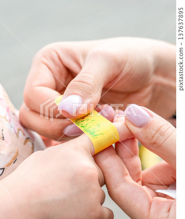Child healthcare routine. Toddler finger bandaged by mother hands. Daily care concept. Child healthcare routine. Toddler finger bandaged by mother hands. Daily care concept. 137637895