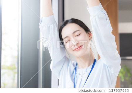 一位女商人坐在辦公室窗邊休息,伸展身體,放鬆身心,周圍環繞著春天清新的綠意。她看起來神清氣爽,精神煥發。 一位女商人坐在辦公室窗邊休息,伸展身體,放鬆身心,周圍環繞著春天清新的綠意。她看起來神清氣爽,精神煥發。 137637953