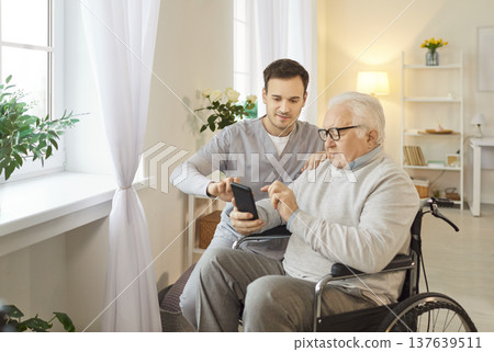 Elderly Patient In Wheelchair With Nurse Spending Leisure Time Using Phone Elderly Patient In Wheelchair With Nurse Spending Leisure Time Using Phone 137639511