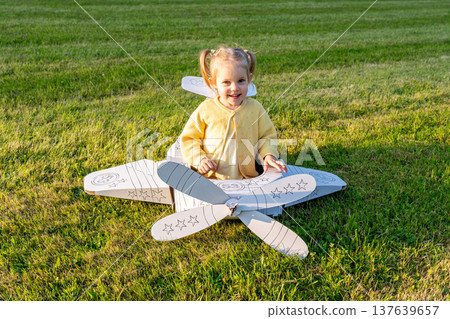 Flying girl. Yellow cardboard costume child. Park activity sunshine toddler. Flying girl. Yellow cardboard costume child. Park activity sunshine toddler. 137639657