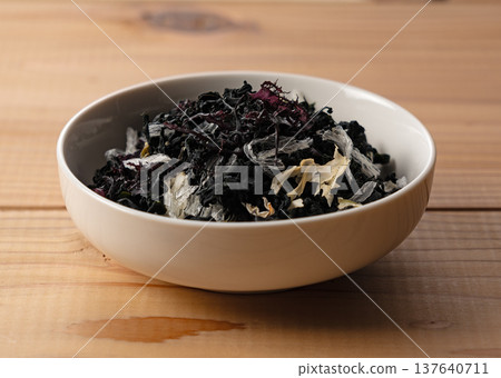 Dried seaweed salad mix served on a white plate Wood grain background 137640711