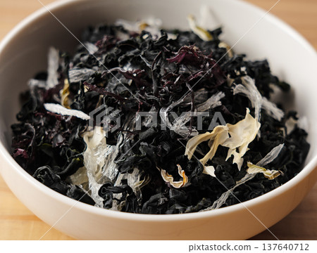 Dried seaweed salad mix served on a white plate Wood grain background 137640712