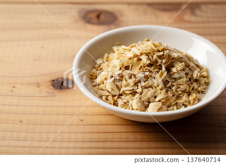 乾燥百合鱗莖片盛放在白色盤子上,背景是木紋。 乾燥百合鱗莖片盛放在白色盤子上,背景是木紋。 137640714