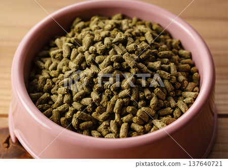 盛放在粉紅色木紋背景盤子上的兔子糧(顆粒狀) 盛放在粉紅色木紋背景盤子上的兔子糧(顆粒狀) 137640721