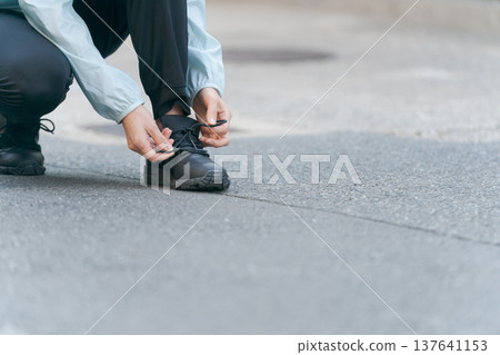 Woman tying shoelaces on sneakers Woman tying shoelaces on sneakers 137641153