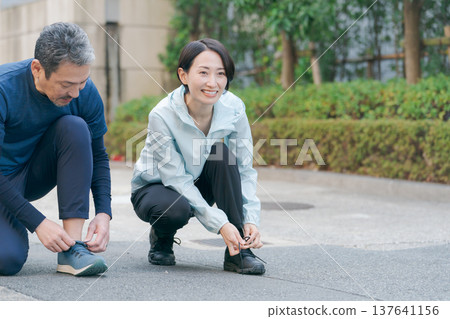 An active couple who tie their shoelaces An active couple who tie their shoelaces 137641156