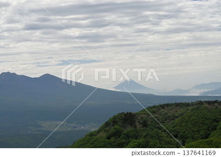 A beautiful view of Mount Fuji rising majestically from the long base of the mountains in the foreground, as seen from the Shinshu Utsukushigahara Plateau. A beautiful view of Mount Fuji rising majestically from the long base of the mountains in the foreground, as seen from the Shinshu Utsukushigahara Plateau. 137641169
