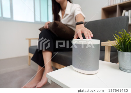 Smart Speaker Control. User adjusting smart speaker settings at home. Smart Speaker Control. User adjusting smart speaker settings at home. 137641480