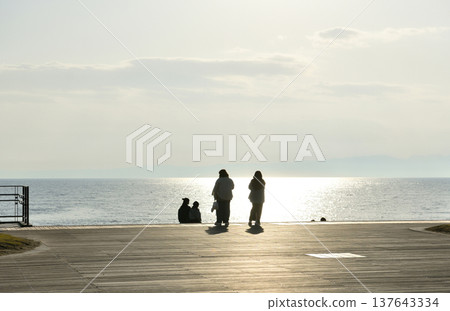夕陽西下時，人們在片瀨西濱海灘的甲板上眺望大海。 137643334