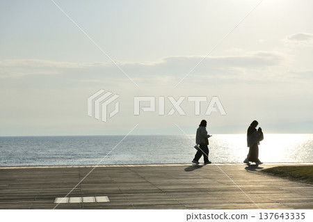 夕陽西下時，人們在片瀨西濱海灘的甲板上眺望大海。 137643335