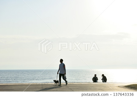 夕陽西下時，人們在片瀨西濱海灘的甲板上眺望大海。 137643336