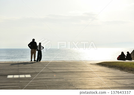 夕陽西下時，人們在片瀨西濱海灘的甲板上眺望大海。 137643337