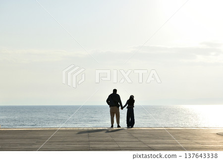 夕陽西下時，人們在片瀨西濱海灘的甲板上眺望大海。 137643338