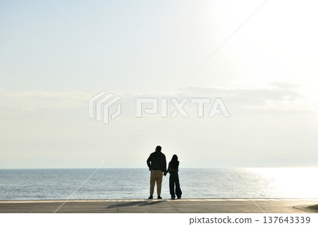 夕陽西下時，人們在片瀨西濱海灘的甲板上眺望大海。 137643339