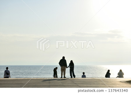 夕陽西下時，人們在片瀨西濱海灘的甲板上眺望大海。 137643340