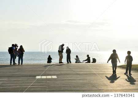 夕陽西下時，人們在片瀨西濱海灘的甲板上眺望大海。 137643341