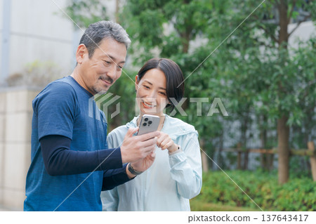 一對穿著運動服的情侶正在看手機。 一對穿著運動服的情侶正在看手機。 137643417