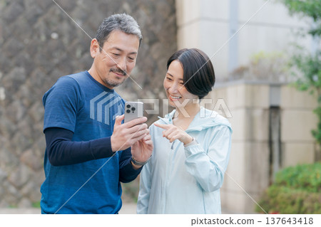 一對穿著運動服的情侶正在看手機。 一對穿著運動服的情侶正在看手機。 137643418